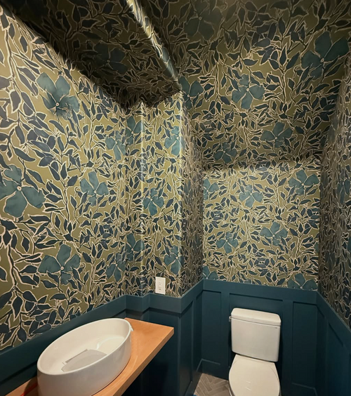 Powder bath with green floral wallpaper and matching wallpapered ceiling