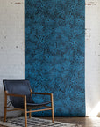 Modern room with black leather armchair, wooden frame, and blue patterned
wallpaper with swirling floral design on a dark background, set on a textured white
rug.