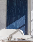 Deep navy-blue wallpaper with light blue vertical wavy lines, behind a boucle sofa and a modern coffee table featuring ceramics and an open book.