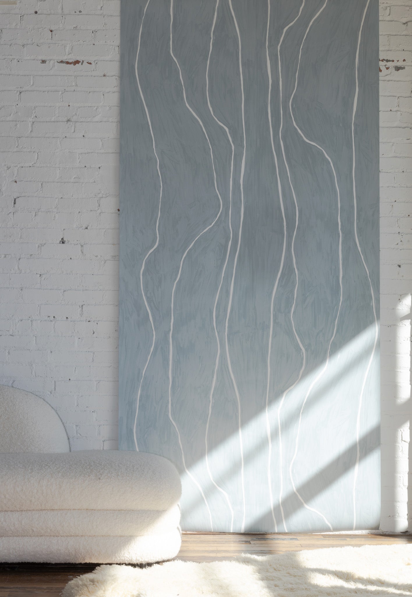 Soft teal wallpaper with white organic vertical lines, styled with a boucle sofa and a light shag rug on a wooden floor.