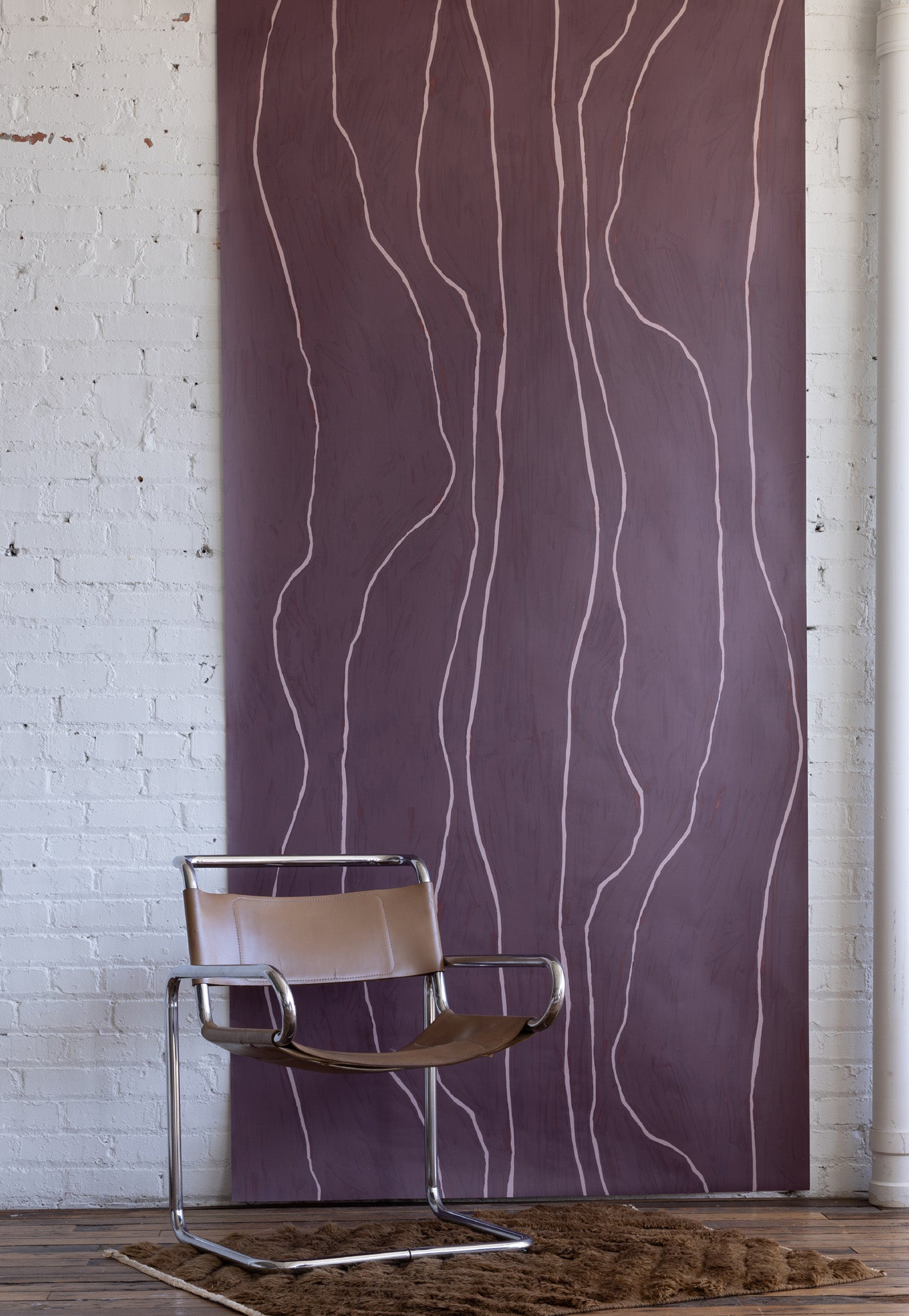 Plum-colored wallpaper with soft pink vertical organic lines, styled with a leather and chrome chair and a deep brown textured rug.